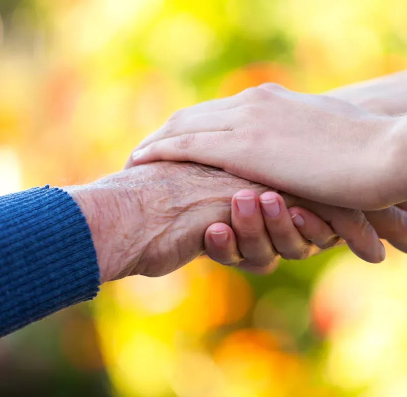 Eine Pflegekraft hält die Hand einer Seniorin, ambulante Pflege in Sankt Augustin